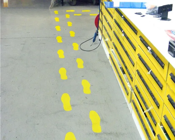 Marcaje pietonale sub formă de pași din autocolant galben pe pardoseală industrială